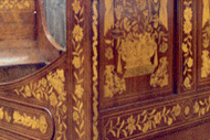 Detail of an intricate inlaid wood bed frame restored in E & A Wates' workshop.
